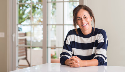 Middle aged woman with a happy face standing and smiling with a confident smile showing teeth