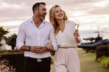 Elegant couple walking outdoors with wine