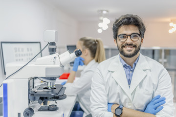 closeup portrait, young friendly scientist standing by microscope. isolated lab background. research