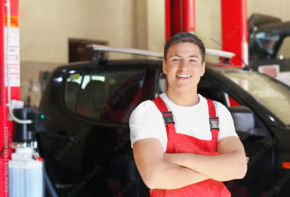 Young auto mechanic near car in service center