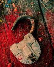 An Open Old Padlock Rests On A Wooden Surface With Traces Of Paint.