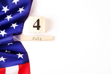 Wall Mural - Ruffled American flag and wooden cube calendar with 4th of July date. Happy Independence Day greeting card template on white copy space background. US patriotic festive composition, top view, close up