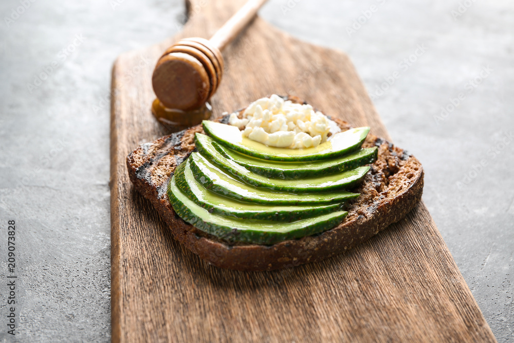 Board with tasty toast on grey background