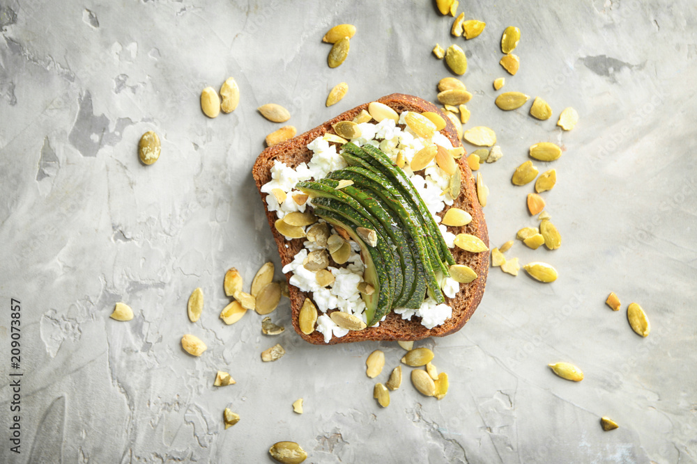 Tasty toast with avocado on grey background