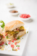 Sticker - Dabeli is an Indian snack item served with Pomegranate Seeds and Cilantro in white ceramic plate. It's a popular Navratri Festival food