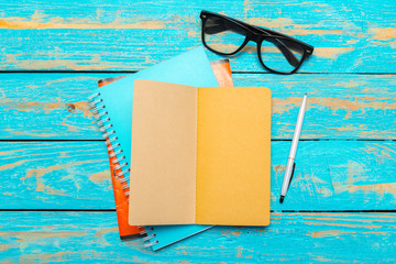 Sticker - Top view workspace with blank notebook and pen on wooden table background