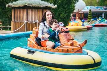 Wall Mural - A happy mother and son are riding on a merry-go-round carousel together, smiling and having fun at a fair or amusement park.