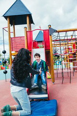 Wall Mural - emotional funny little boy and mother in the amusement park. children outdoors. vacation in the summer park