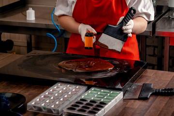 Step-by-step preparation of black designer candies. Preparation of chocolate glaze decorations for candy.