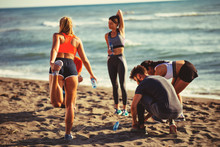 Group Of Young People Is Warming Up Before Jogging On The Beach By The Sea