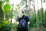 Fototapeta Na ścianę - Young girl traveler with backpack and looking at forest.