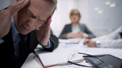 Male worker has migraine attack caused by stress and exhaustion at workplace