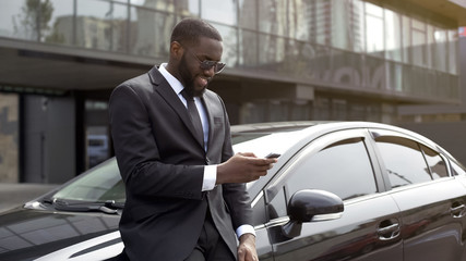 Masculine man in expensive suit waiting for companion, scrolling news on gadget