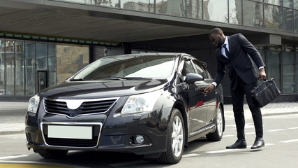 Rich African American man opening door of luxury car with special key, security