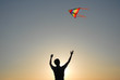 © ruslanshug - young man with colorful flying kite on summer warm sunset outdoors