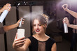 © luckyphoto - beautiful happy model with perfect makeup and coiffure is having fixation with hair sprays. four hands holding and pulverizing bottles. girl is taking a photo of herself