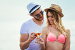 © Mediteraneo - Happy young couple lying on a beach and drinking champagne