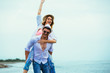 © Mediteraneo - Happy couple in love on beach summer vacations. Joyful girl piggybacking on young boyfriend having fun.