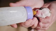 © StockMediaSeller - A woman is feeding from a bottle of a newborn puppy. Caring and protection concept