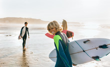 Three Teenage Friends Heading Out To Sea For Surfing