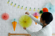 © Nabi Tang/Stocksy - Asian young woman decorating house with multicolored diy tissue paper decoration lantern