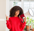 © Krakenimages.com - African american woman holding megaphone speaker very happy pointing with hand and finger to the side