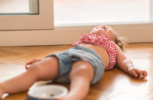 Beautiful Blond Child Crying And Shouting With Tantrum Laying On The Floor At Home.