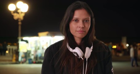 Wall Mural - Close up portrait of millennial woman in bomber jacket on the street at night, Caucasian female hipster in bomber jacket looking at camera in urban setting, 4k