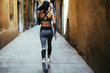 © Bonninstudio/Stocksy - Back view of a young woman running on the street. Urban life.