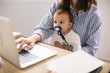 © Bonninstudio/Stocksy - Young mother taking care her baby while working at home.