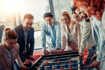 Poster - Colleagues playing table football in modern office