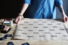 Woman Making Homemade Christmas Gift Wrap Paper With Ink Stamp And Brown Paper.