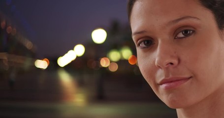 Wall Mural - Close up portrait of beautiful Caucasian woman in urban setting with bokeh lights, Young and attractive brunette female outside at night smiling at camera, 4k