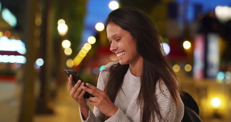 Wall Mural - Millennial woman in grey sweater on Champs-Elysees taking selfie with mobile phone, Female backpacker takes travel photo while on Paris street at night, 4k