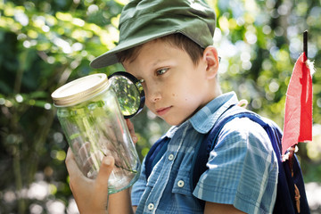 Wall Mural - Boy examining a plant with a magnifying glass