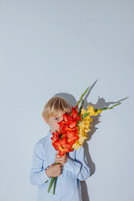 Lovely Blond Boy Hiding Half Of His Face With Gladiolus Flowers Bouquet