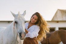 Happy Young Woman Caressing A White Horse