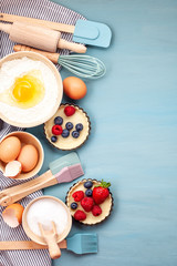 Wall Mural - Baking utensils and cooking ingredients for tarts, cookies, dough and pastry. Flat lay with eggs, flour, sugar, berries.Top view, mockup for recipe, culinary classes, cooking blog.