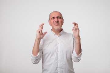 Wall Mural - europeam italian mature man crossing his fingers making a wish. he wanted to win. concept of positiv