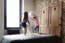 Siblings Having Pillow Fight On Bed
