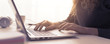 Woman sitting at desk and connecting with her laptop, she is working and typing on the keyboard, hands close up