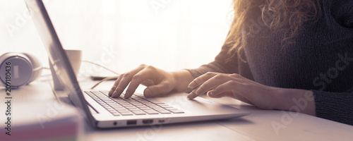 Fotografía Woman sitting at desk and connecting with her laptop, she is working and typing