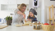 © KONSTANTIN SHISHKIN - Cheerful little girl with her mom mixing the dough in glass bowl for cooking biscuits