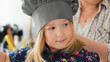 © KONSTANTIN SHISHKIN - Cute little girl chef in hat smiling at cooking studio