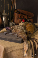 Pheasant And Duck Lay On An Old Wooden Board And Next To A Bunch Of Grapes And A Hunting Bag In A Low Key Scene