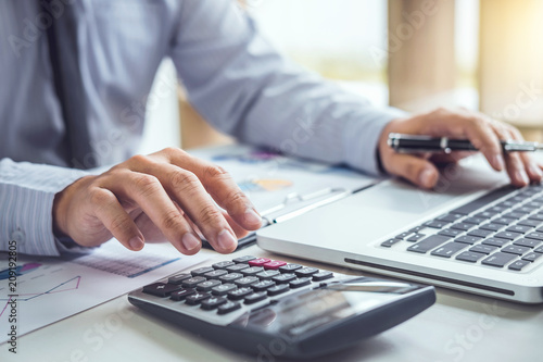 Fotomural Business man or accountant working Financial investment on calculator with calcu
