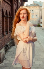 Wall Mural - Gorgeous red haired girl with naked shoulders posing at the city street