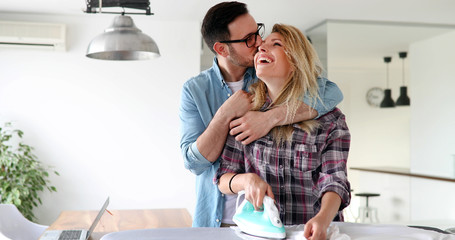 Young couple at home doing hosehold chores and ironing