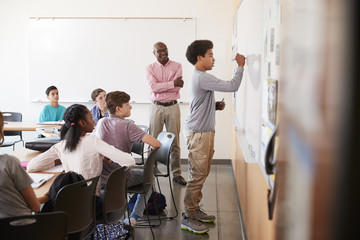 Wall Mural - View Through Doorway Of High School Pupil Writing On Whiteboard In Class