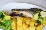 Fototapeta Sypialnia - baked potatoes in a pan, fried fish cod, green lettuce with spices,